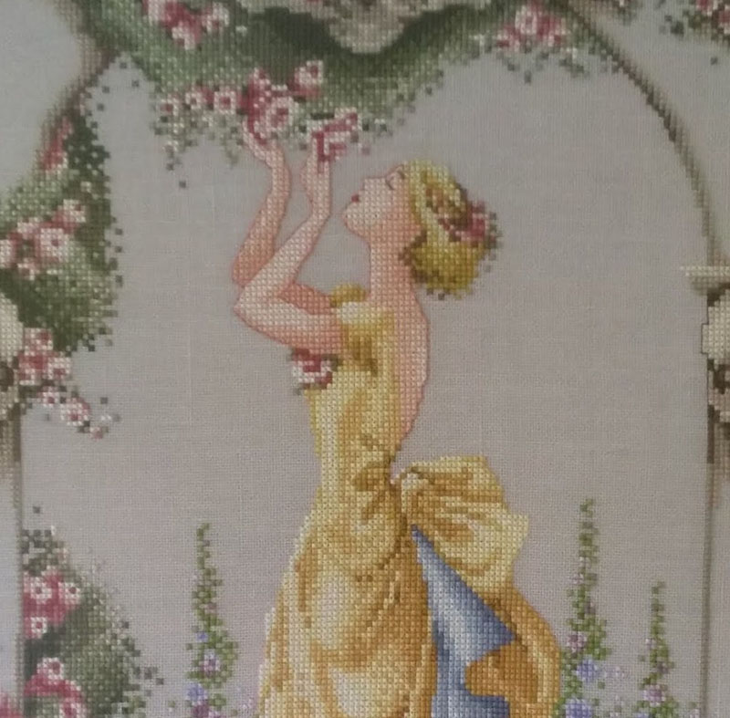 cross stitch of a lady smelling roses