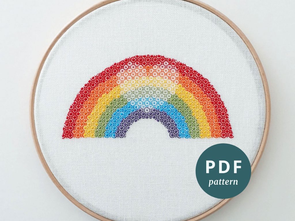 Blackwork embroidery of a rainbow with a shaded heart in the centre.