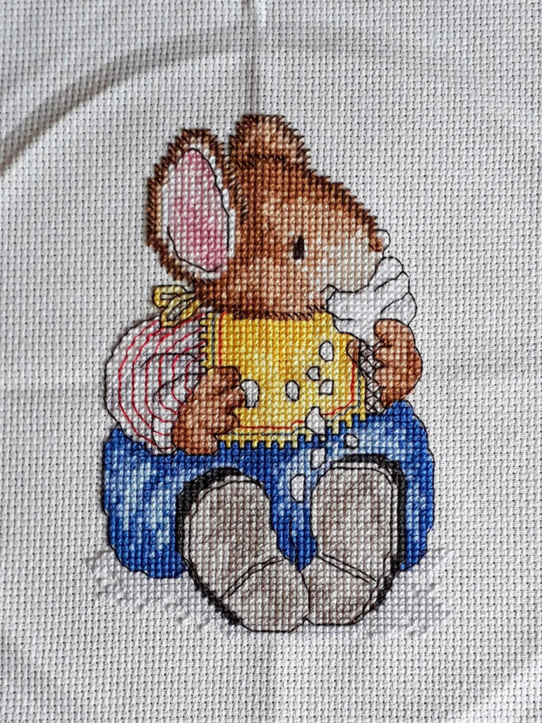 Cross stitch of a mouse eating and ice cream.