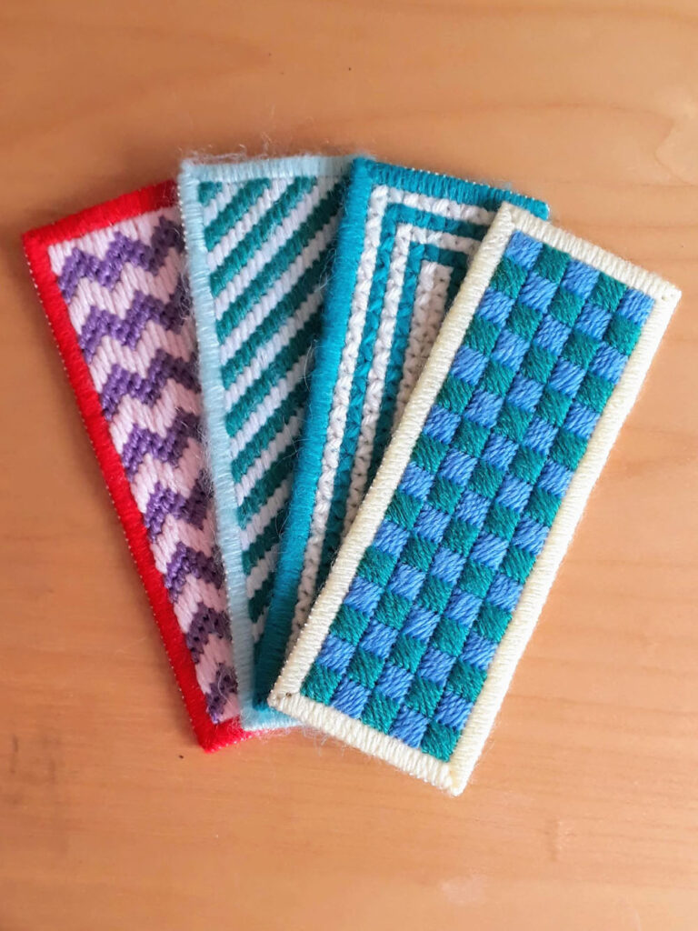 Four embroidered bookmarks, each showcasing a different stitch.