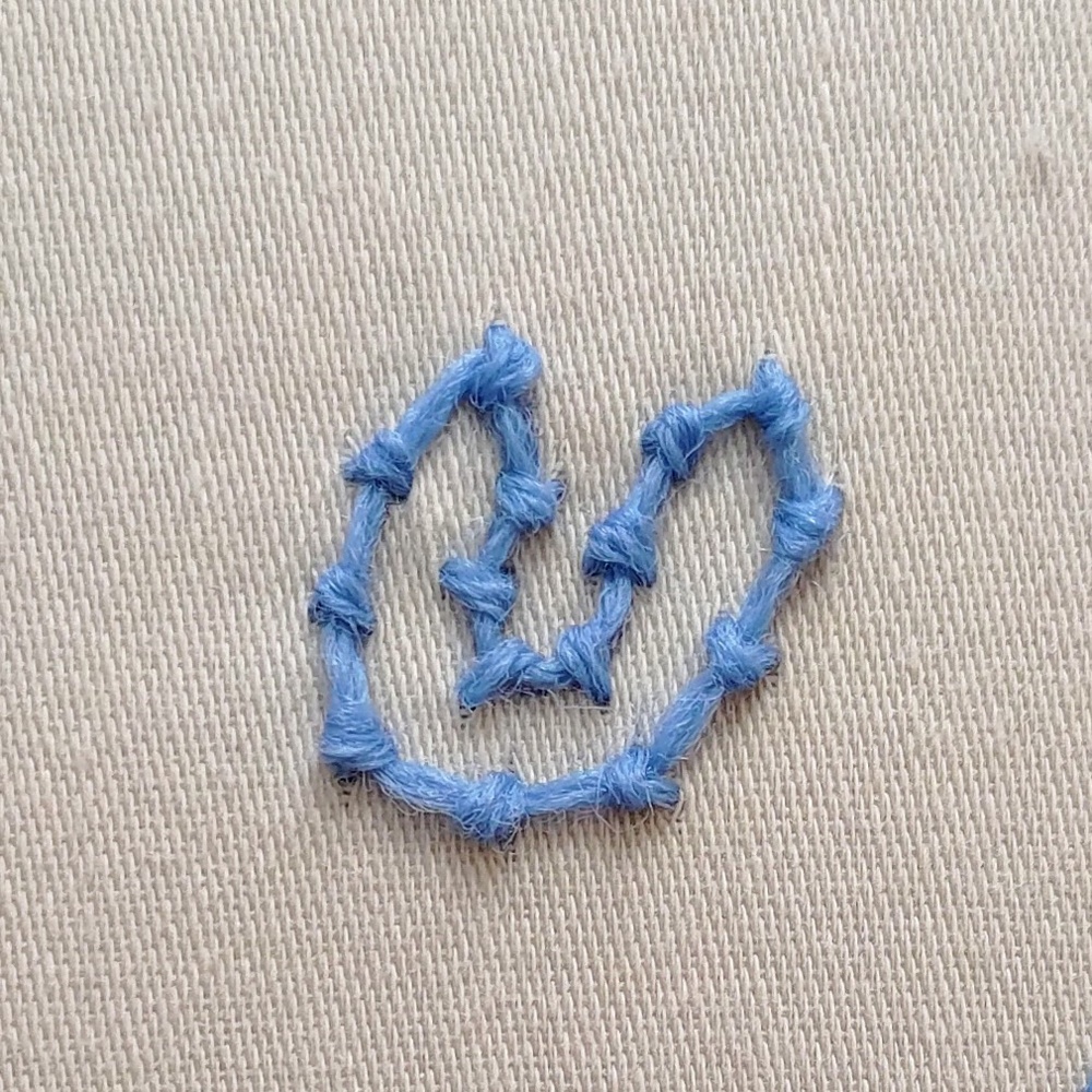 A shape with tight and loose curves stitched in coral stitch.