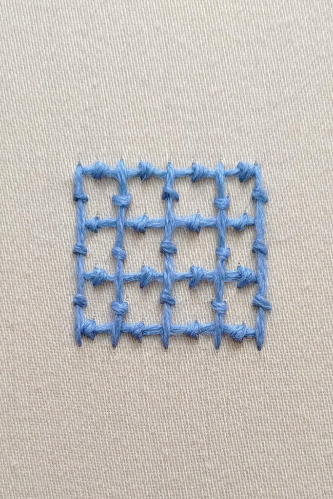 A square grid worked with horizontal and vertical lines of coral stitch.