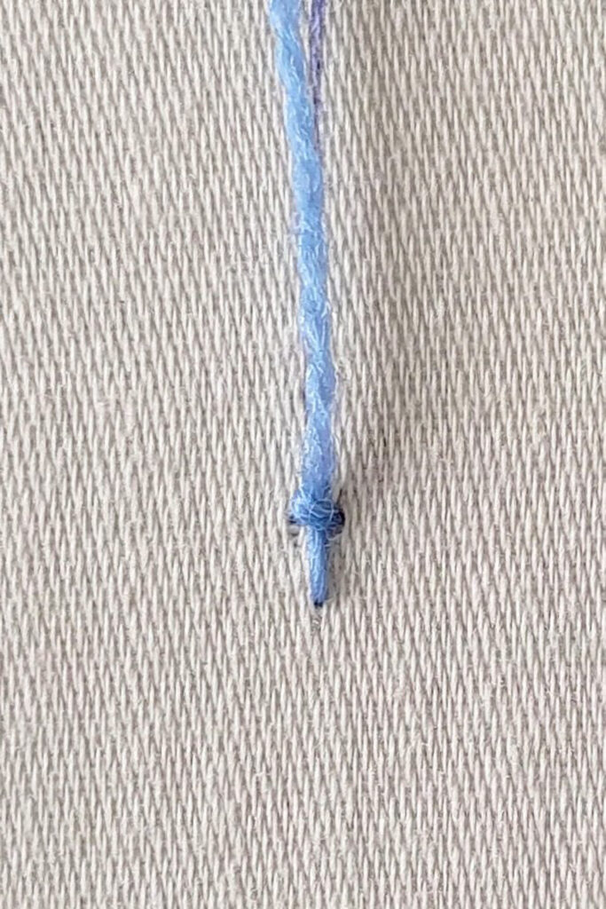First coral stitch worked, with thread ready to work the next stitch.