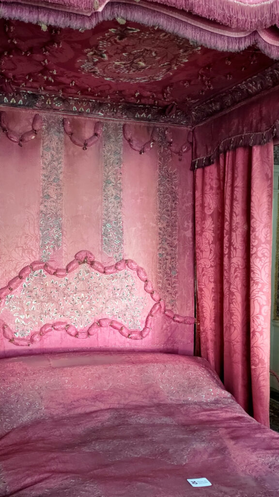 Pink 4 poster bed with embroidered details on the headboard and canopy ceiling.