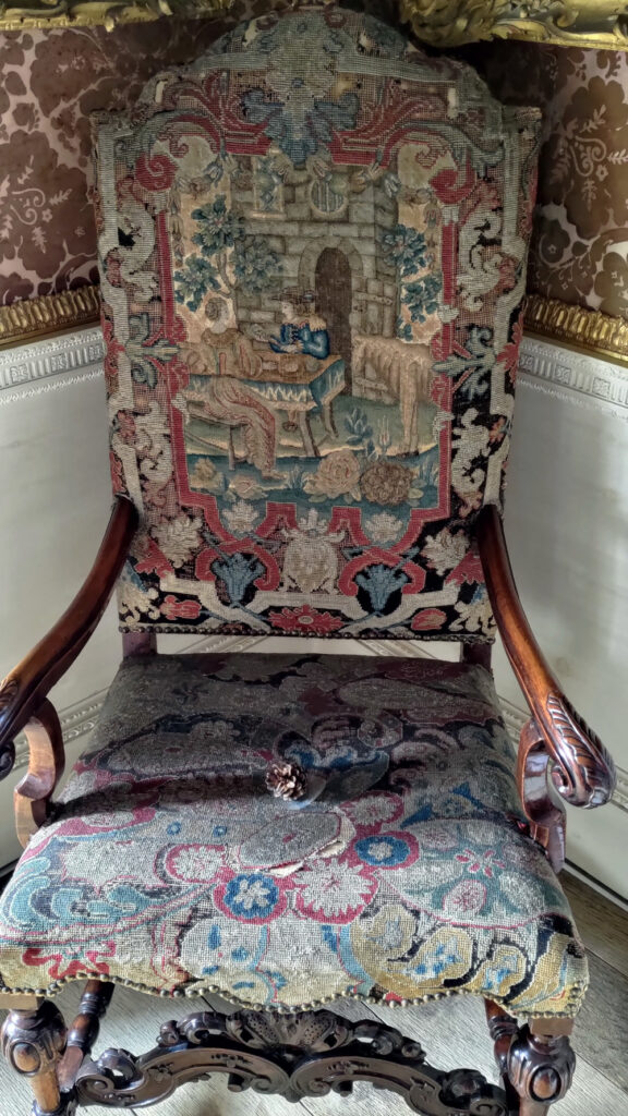 Chair with dark wood arms, the back and seat are upholstered with embroidered fabric.