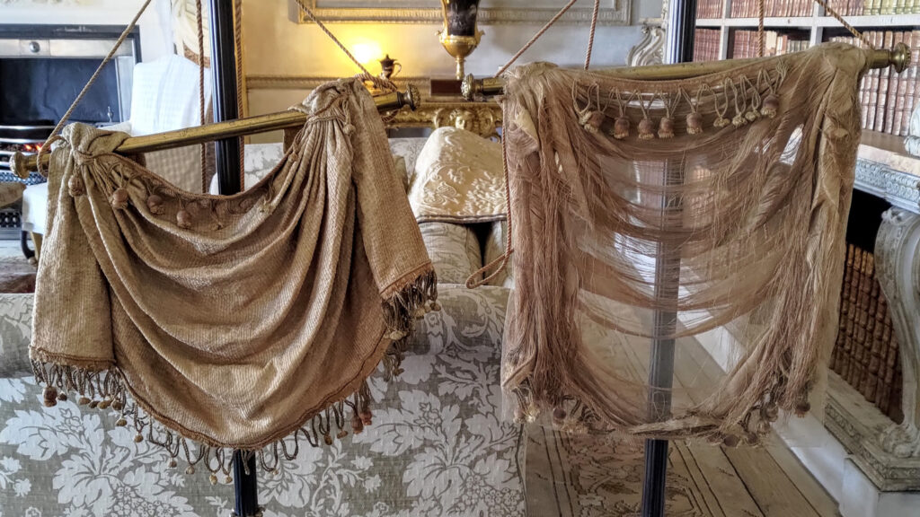 A pair of bronze silk banner screens. The screen on the left has been restored and the fabric looks intact. The screen on the right hasn't been restored and you can see the through the fabric were the threads are hanging loose.