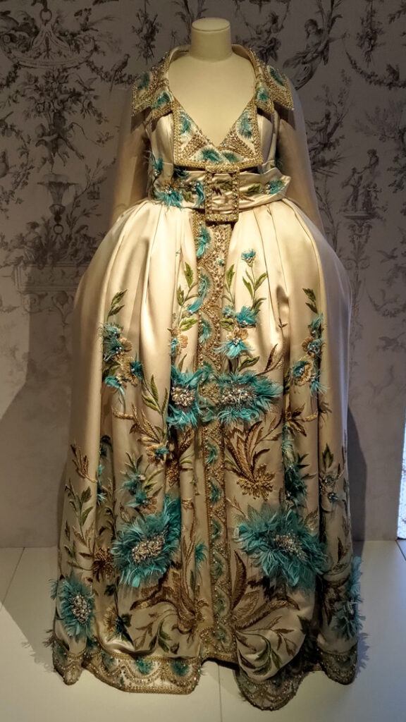 An 18th century inspired coat in a cream fabric that's been heavily embellished with gold and turquoise embroidery.