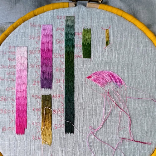Bars of long and short stitch colour sampling in shades of pink, purple, greens and golds. On the right is silk shading sampling of a stem and the top of a flower petal.