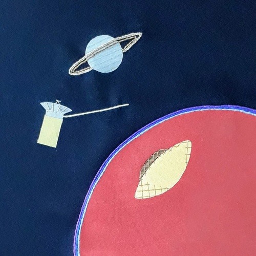 Applique and embroidery design showing the Huygens lander separated from the Cassini satellite and descending towards Titan, Saturn is in the background.