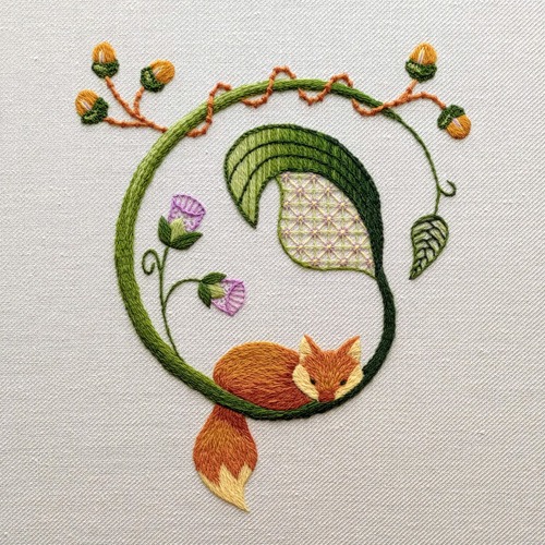 Crewel embroidery of a fox lying on the base of a curved stem that's adorned with acorns, flowers and leaves.