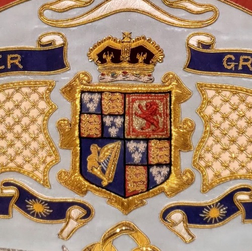 Close up detail of a coat of arms worked in goldwork embroidery.