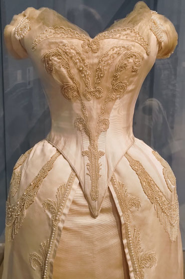 Close up front view of a white evening dress embellished with many embroidered pearls.