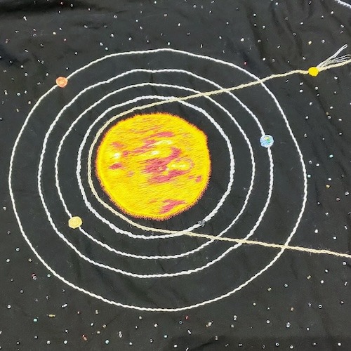 The inner part of the solar system quilt with the Sun at the centre and four circles, each with a different coloured planet stitched on it.