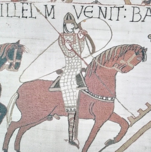 Embroidery of a soldier wearing chainmail sitting on a red horse.