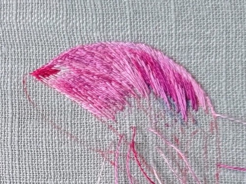 Partially worked flower petal stitched in pinks and purples using the silk shading technique.