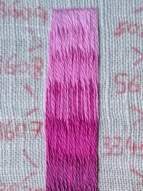 A vertical block of embroidered stitched in straight, vertical stitches graduating from light pink at the top to dark pink-purple at the bottom.