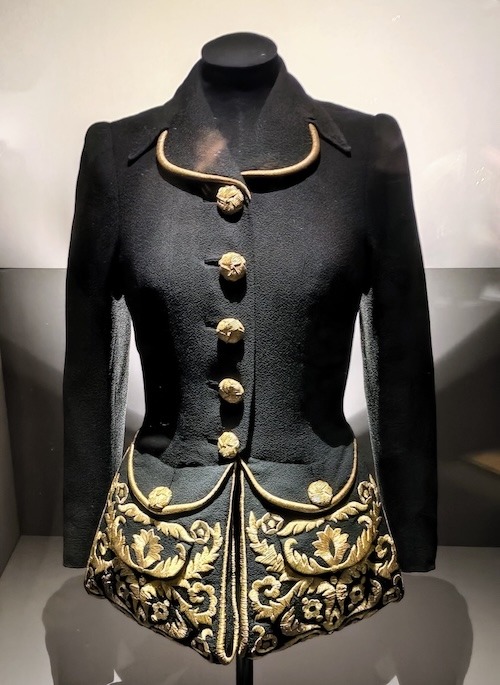Photo of a black jacket with goldwork embroidery embellishment on very large pockets.