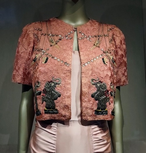 Pink short sleeved jacket embroidered with circus elephants and acrobats.