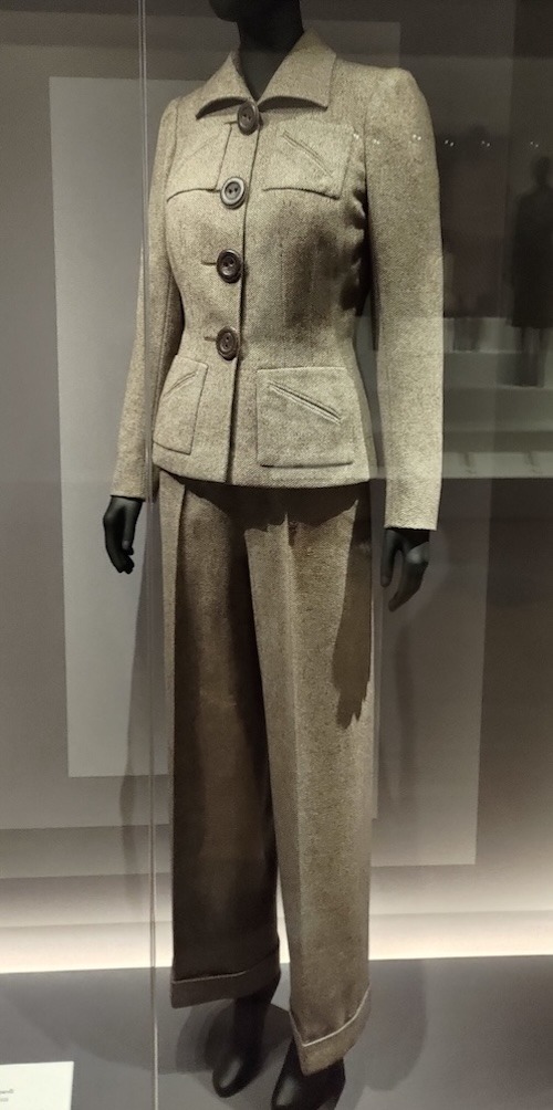 Photo of a light coloured trouser suit featuring large buttons and four square patch pockets with diagonally welt pockets.