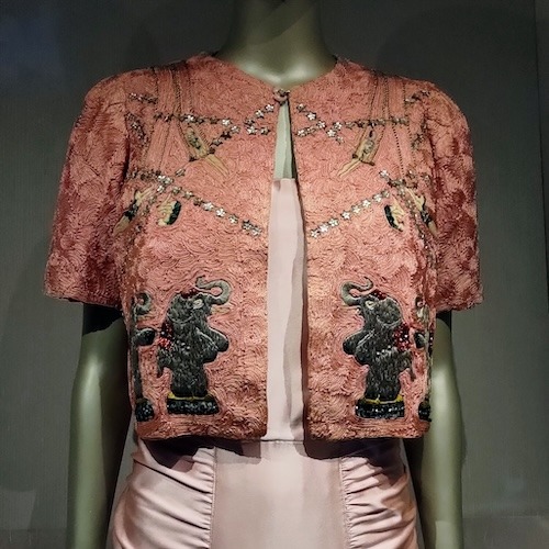 Pink short sleeved jacket with embroidery of circus elephants and acrobats.